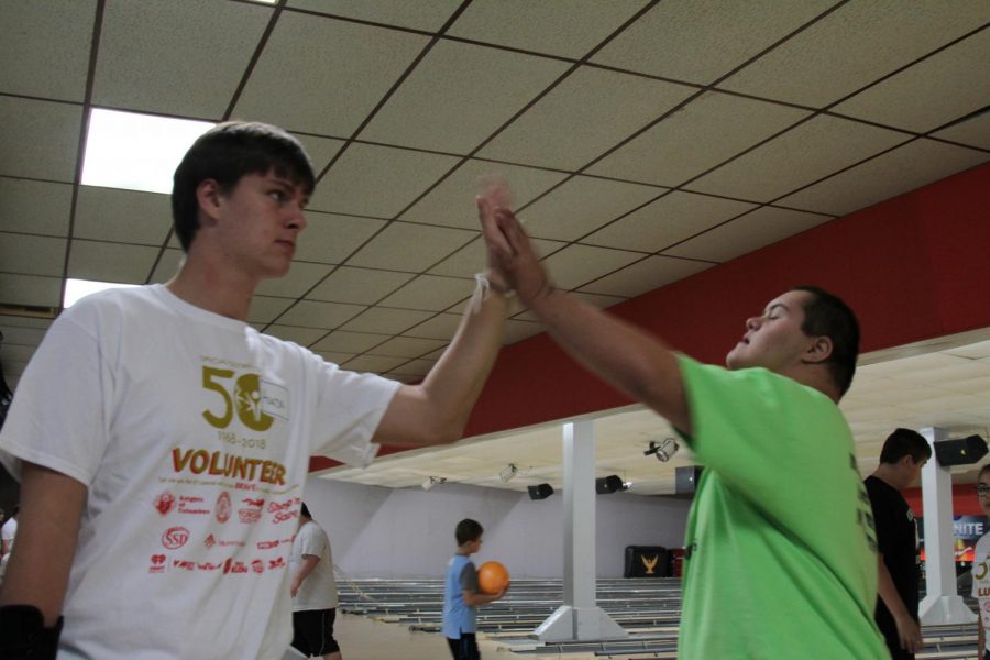 Senior Aaron Harrison gives his brother, eighth grader Alex Harrison, a high five during the Special Olympics on Monday. 